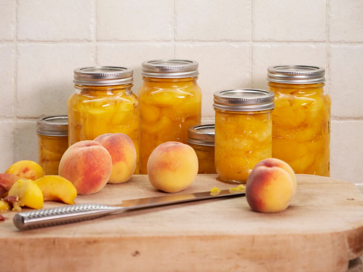 Fresh and canned peaches on a kitchen counter