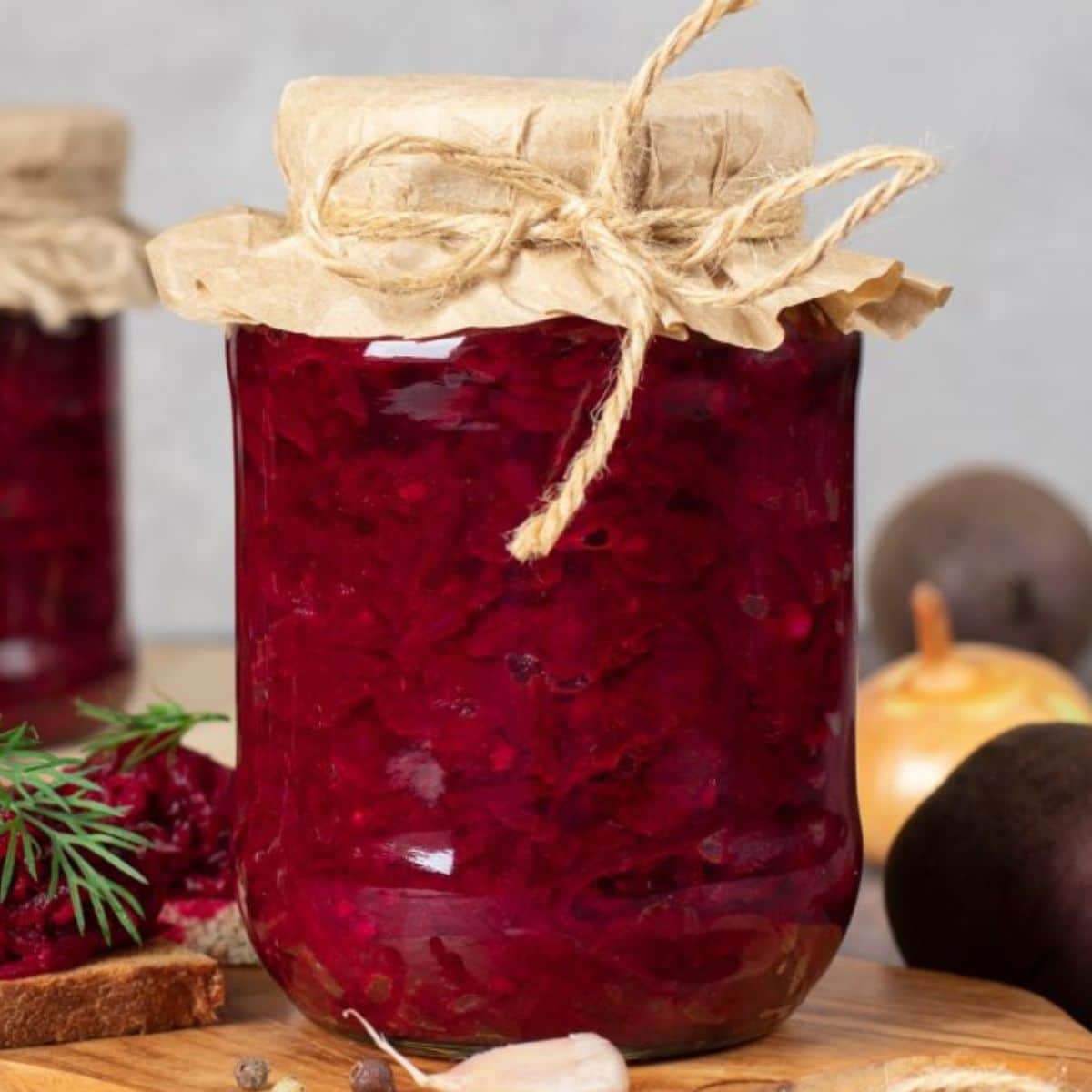 A glass jar of picked beets on a table.