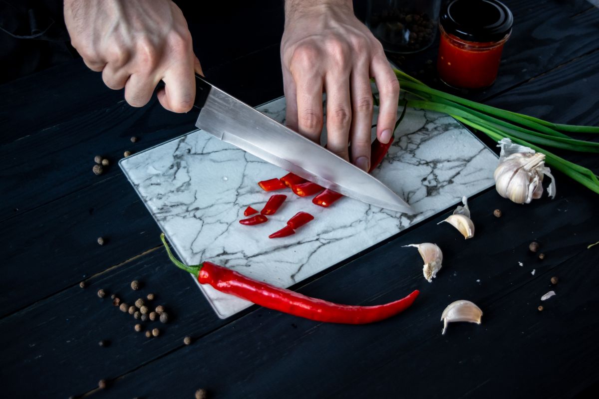 A person prepping hot peppers and vegetables to make hot sauce