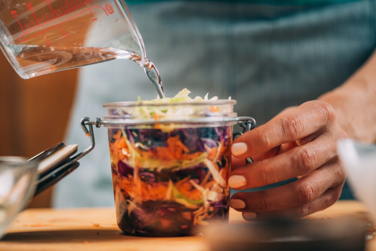 A woman preparing a jar for lacto-fermentation