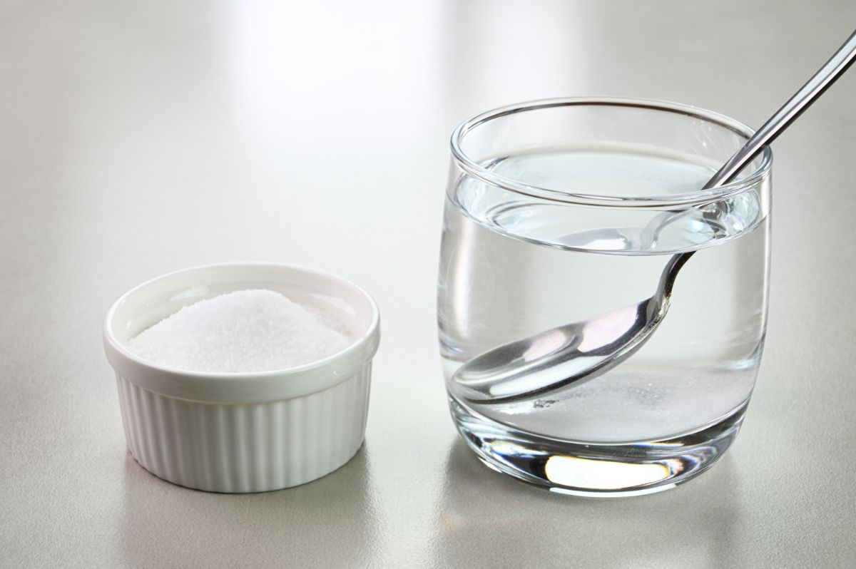 A glass of water and a bowl of salt on a table.