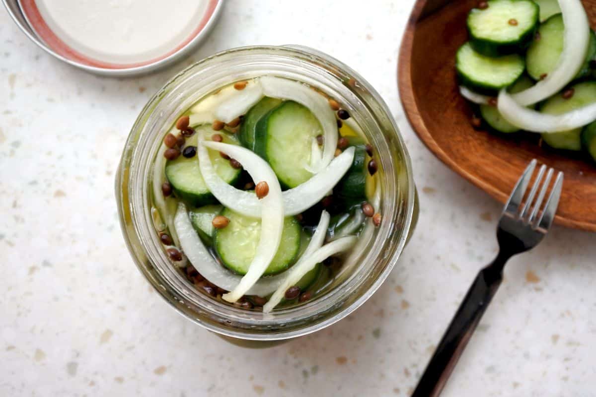 A freshly open jar of refrigerator pickles with onion
