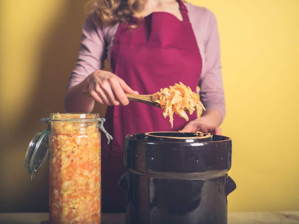 A woman transferring lacto-fermented foods into a crock