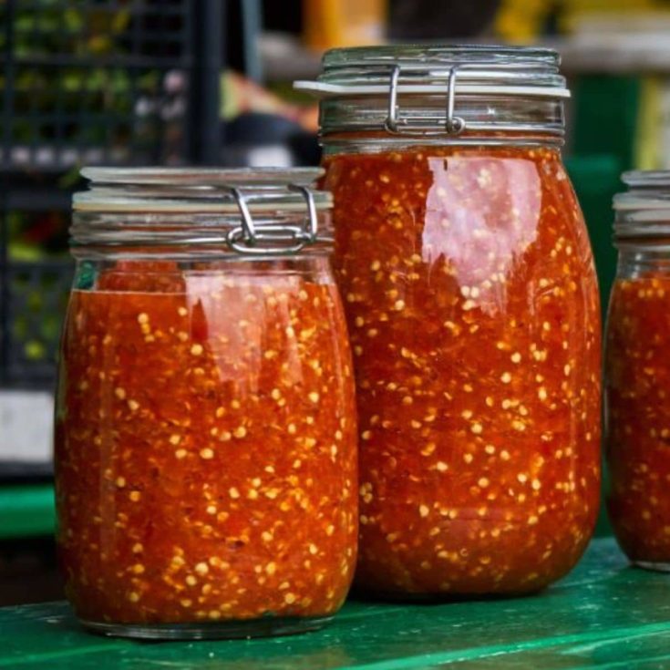 Fermented hot sauce in glass jars on a table.