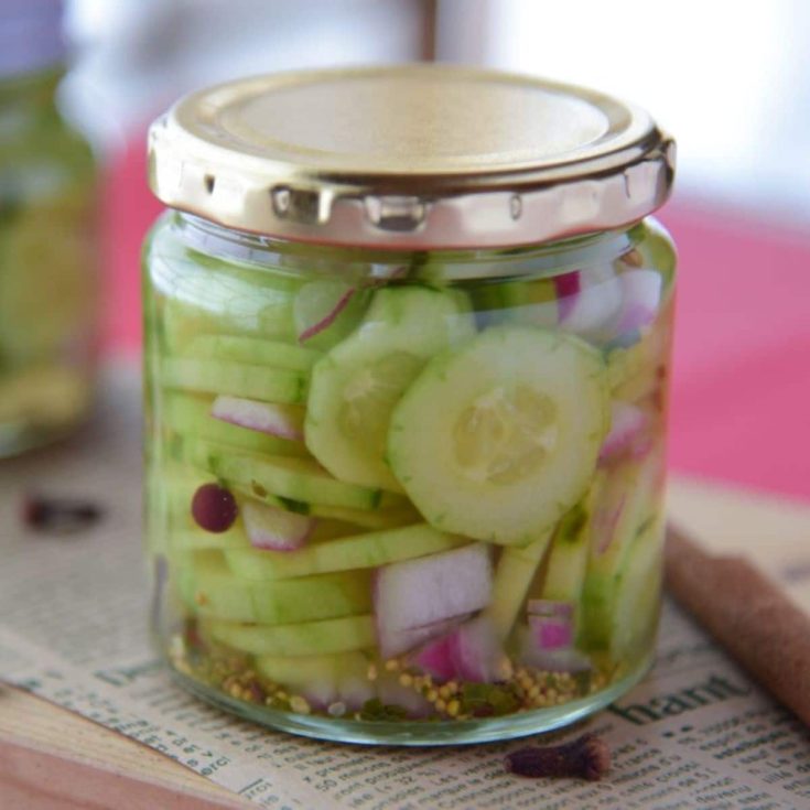 Pickled cucumbers in a glass jar on a table.