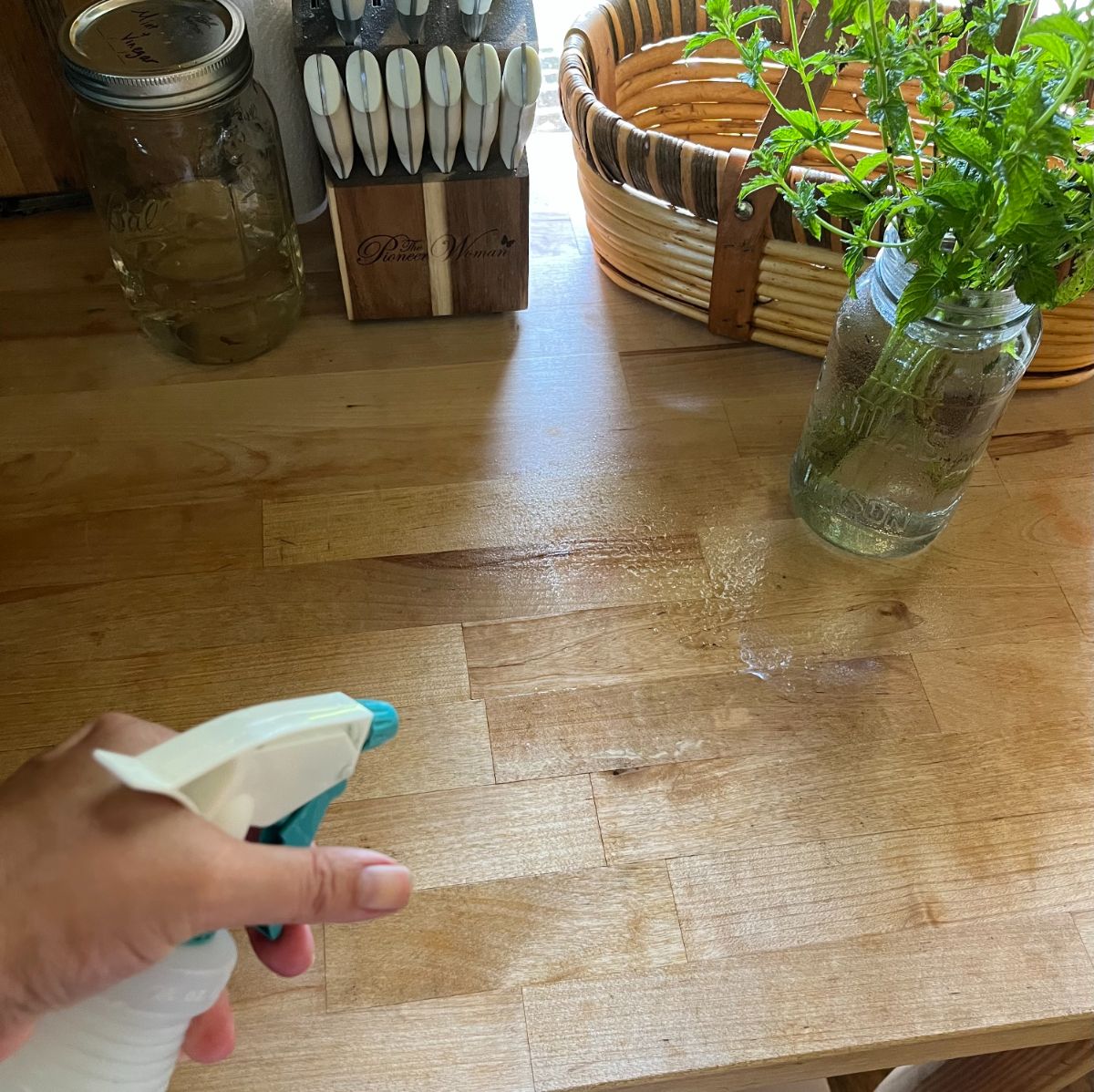 A woman spraying mint vinegar cleaner on a countertop