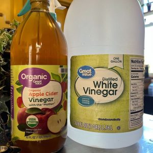 Two bottles of vinegar on a table.