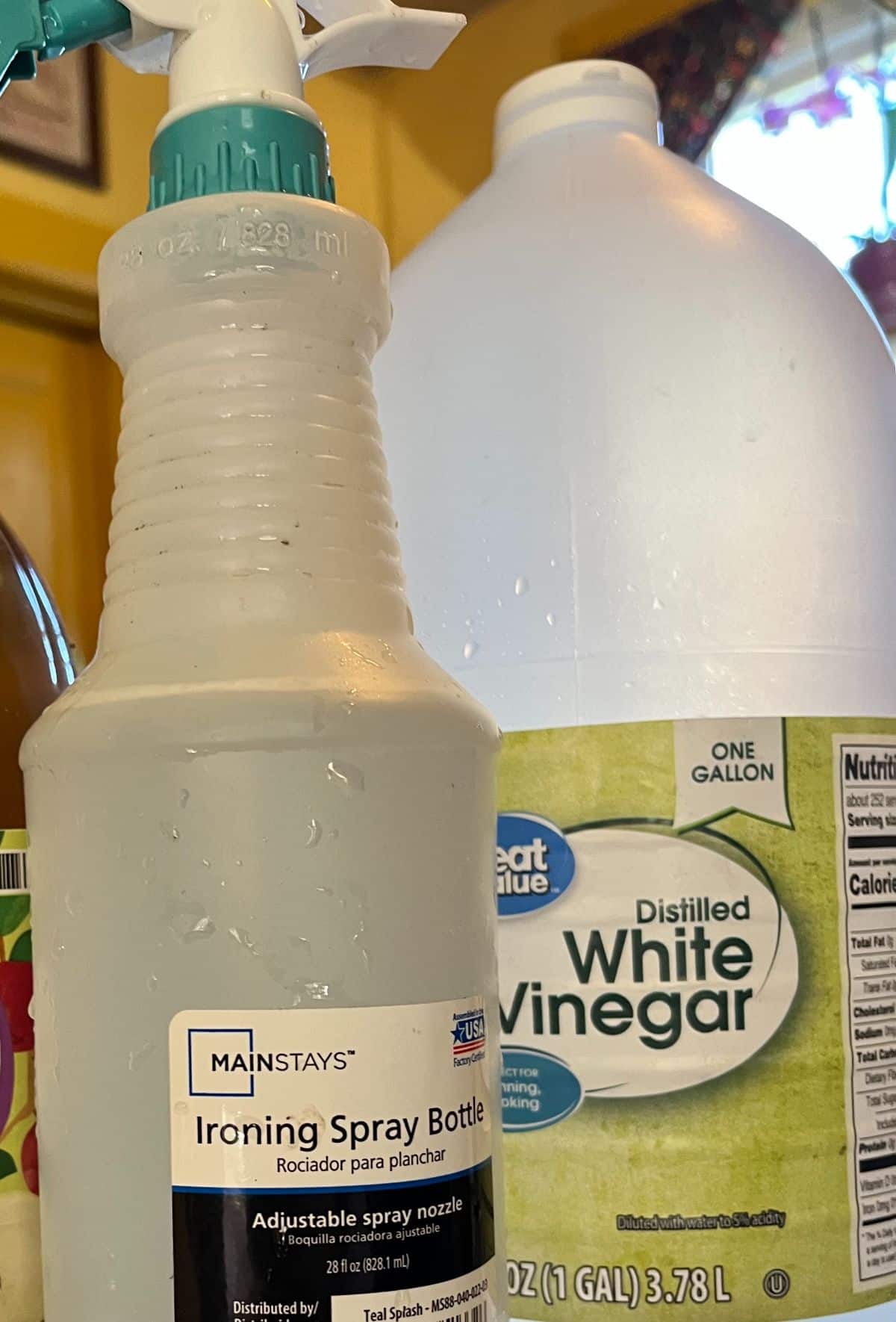 A small spray bottle next to a bottle of normal distilled white vinegar