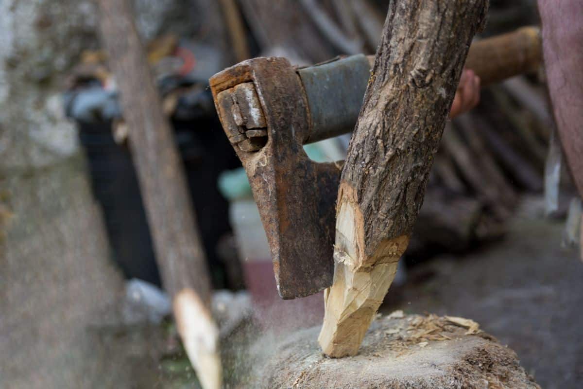 A person sharpening points on the end of stakes for a hedge