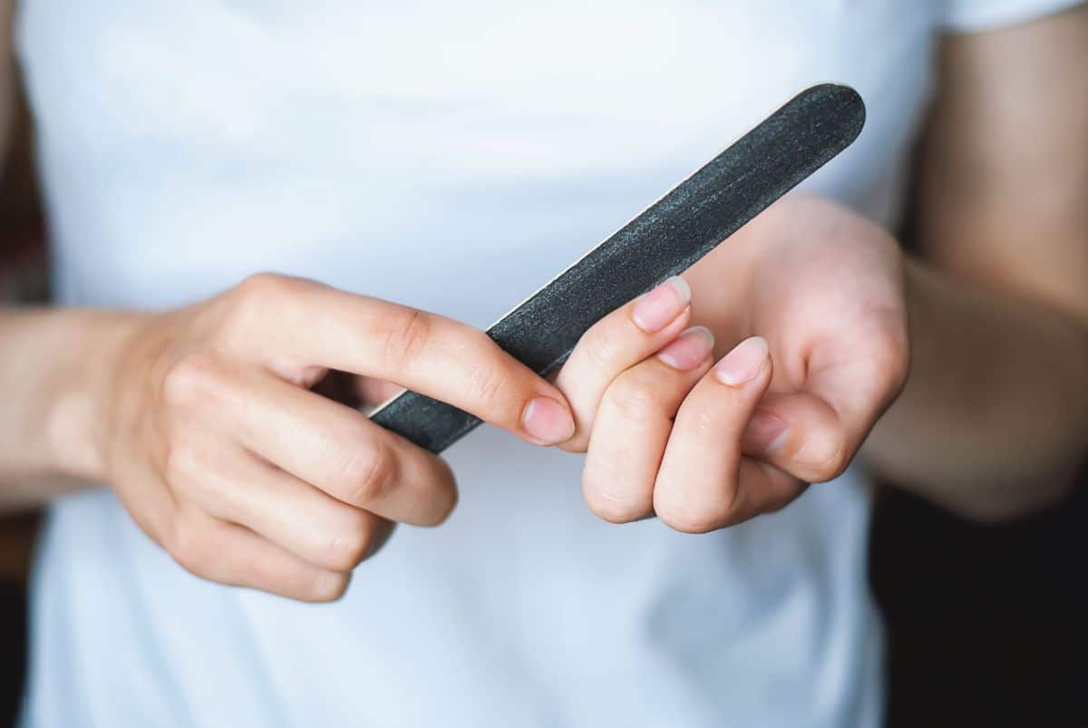 A woman files her fingernails
