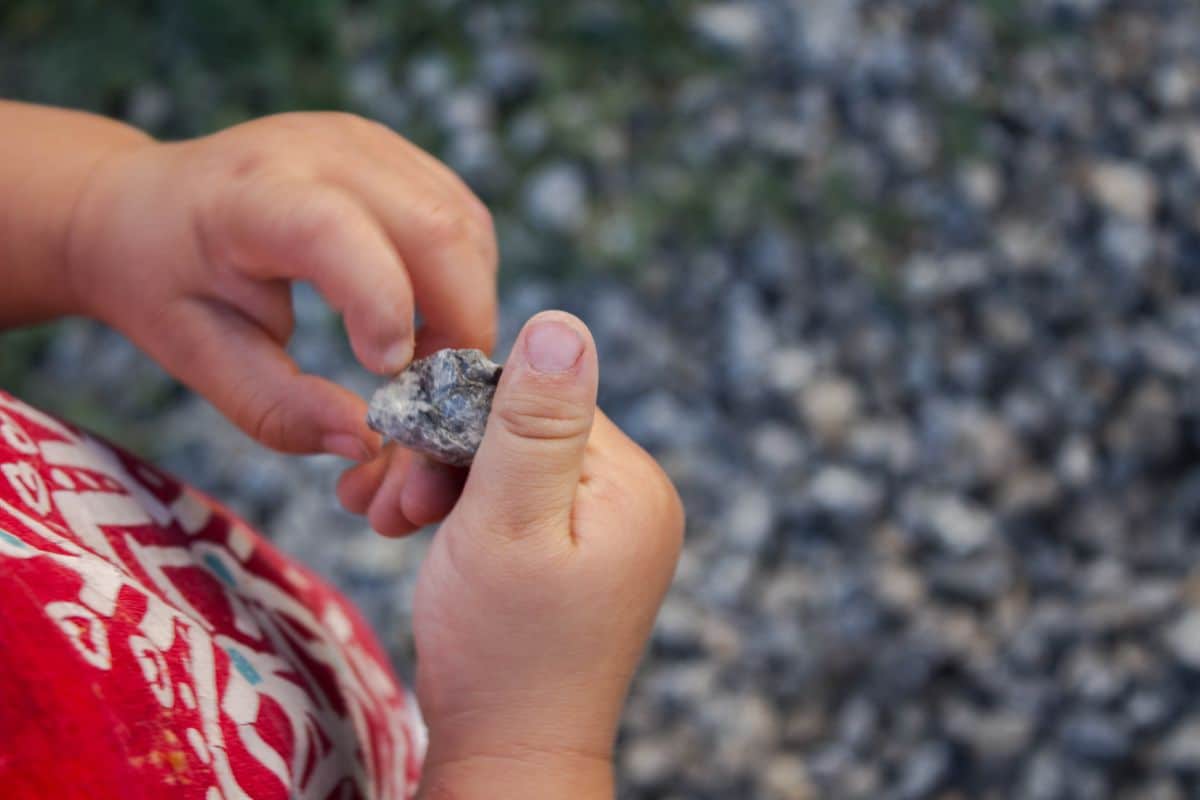 A child looks at a rock in a garden