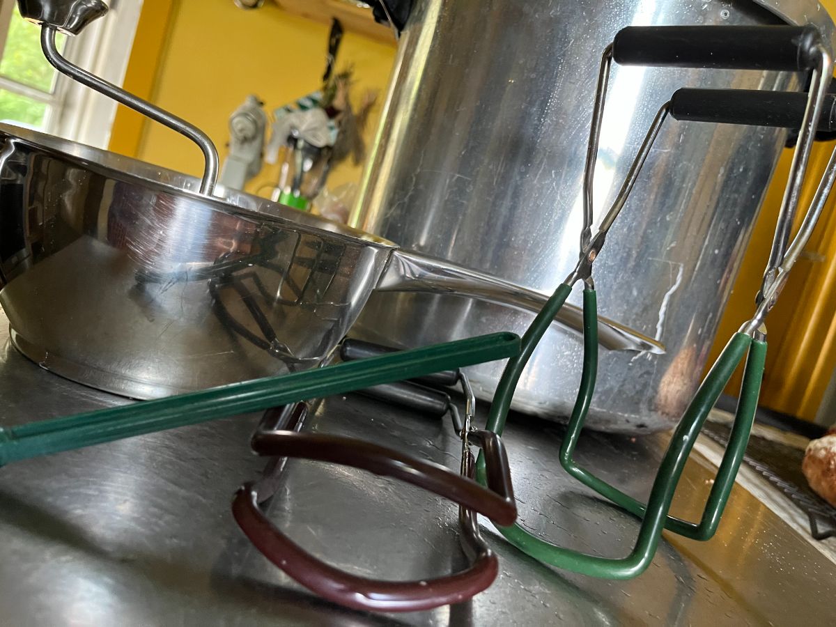 A brown and a green canning jar lifter on a counter