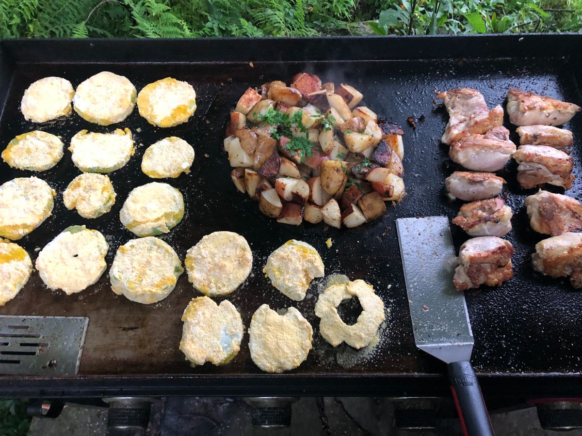 Fried green tomatoes cooking on a flat top grill