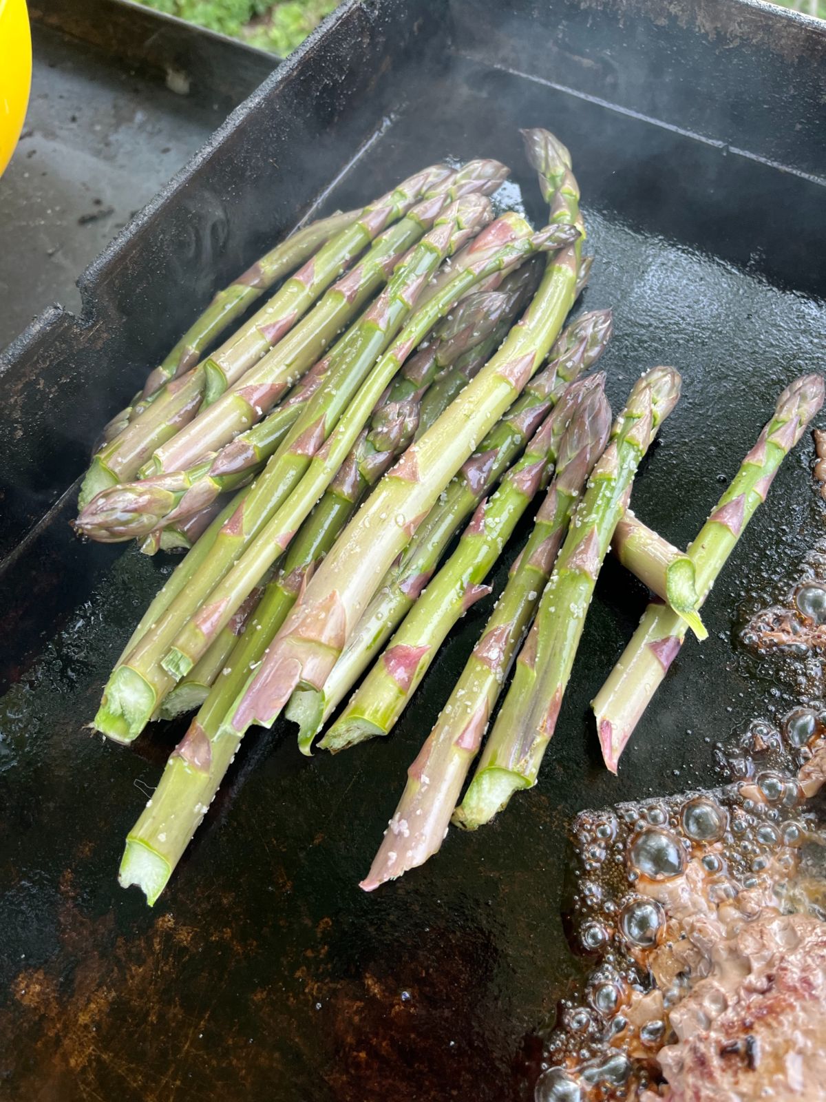 Asparagus cooking on a flat top grill
