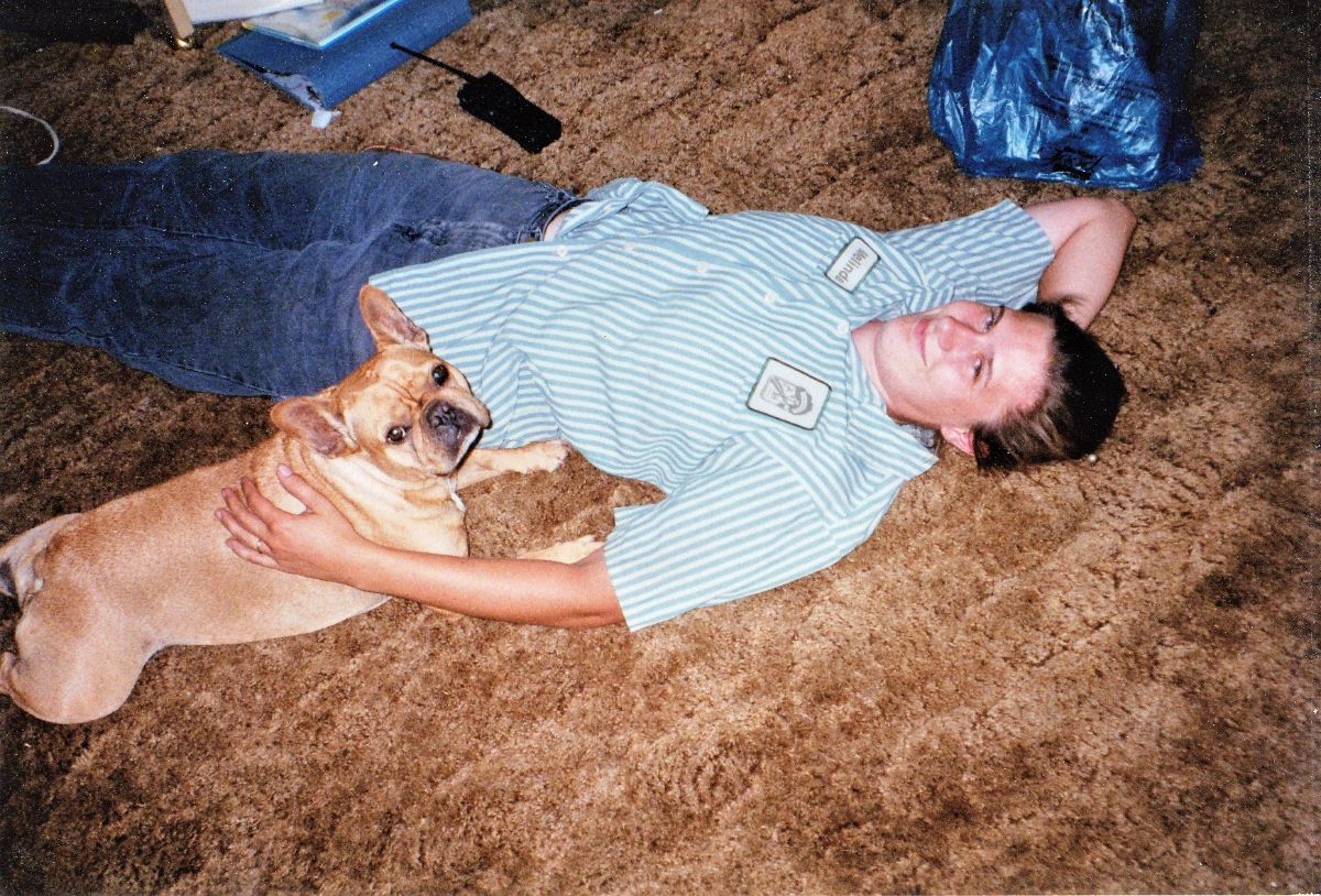A woman and dog lay on a carpet