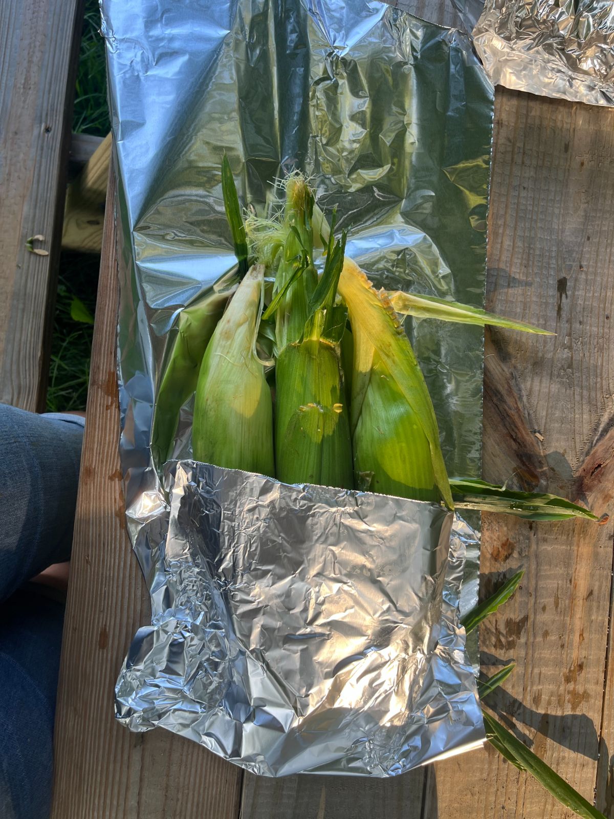 Ears of corn being wrapped for roasting on the flat top grill