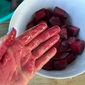 MIxing cut beets with hand in a bowl.
