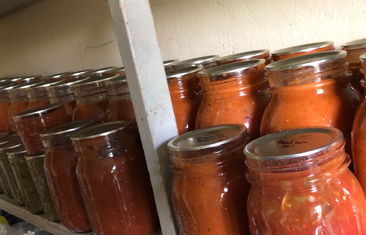 Canned salsa and tomato puree on a pantry shelf