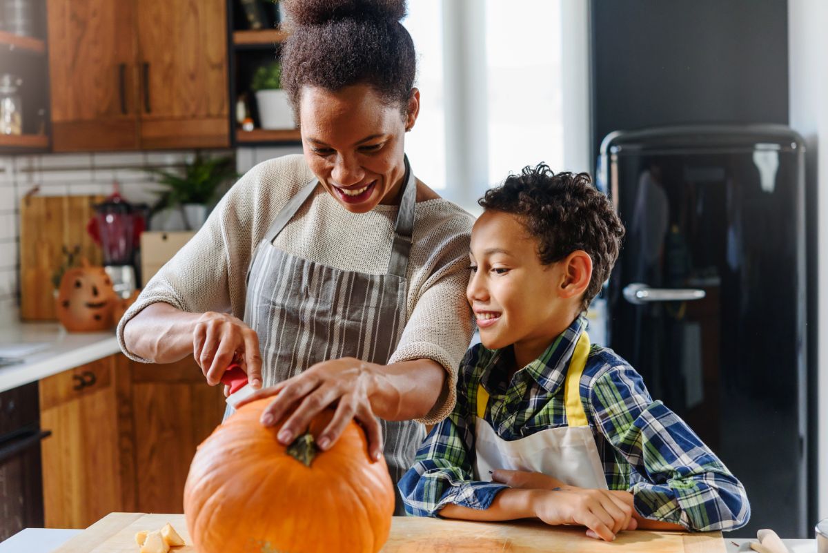 A mother and child carve a pumpkin