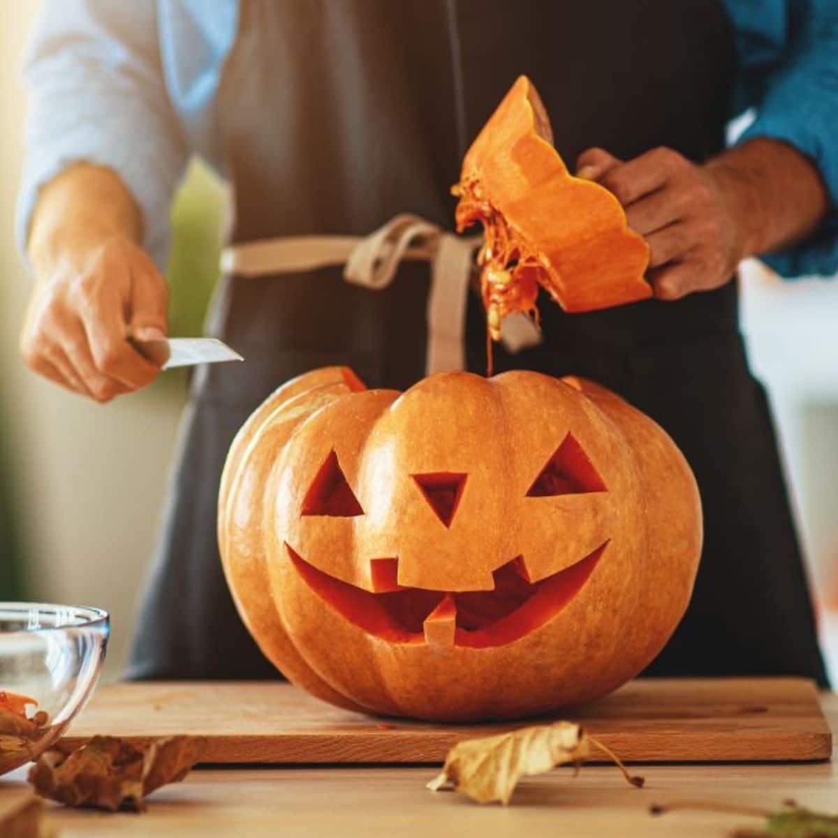 A man cutting a pumpkin for Halloween.