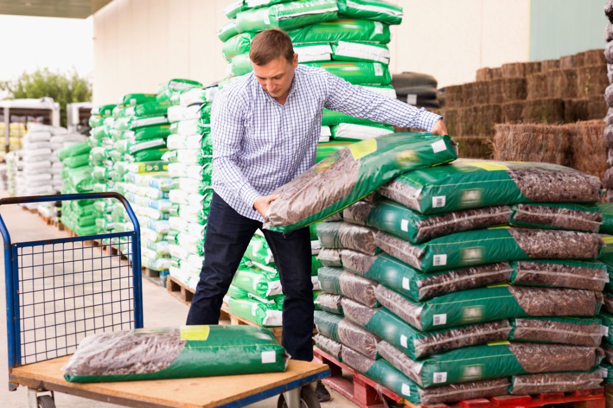 A man loads bags of mulch on a cart