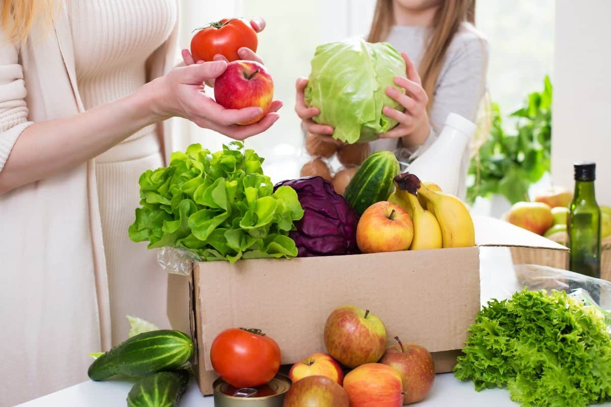 A woman goes through a CSA box of produce
