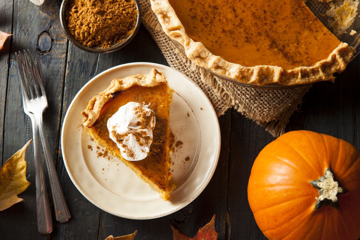 A slice of homemade pumpkin pie next to a pumpkin