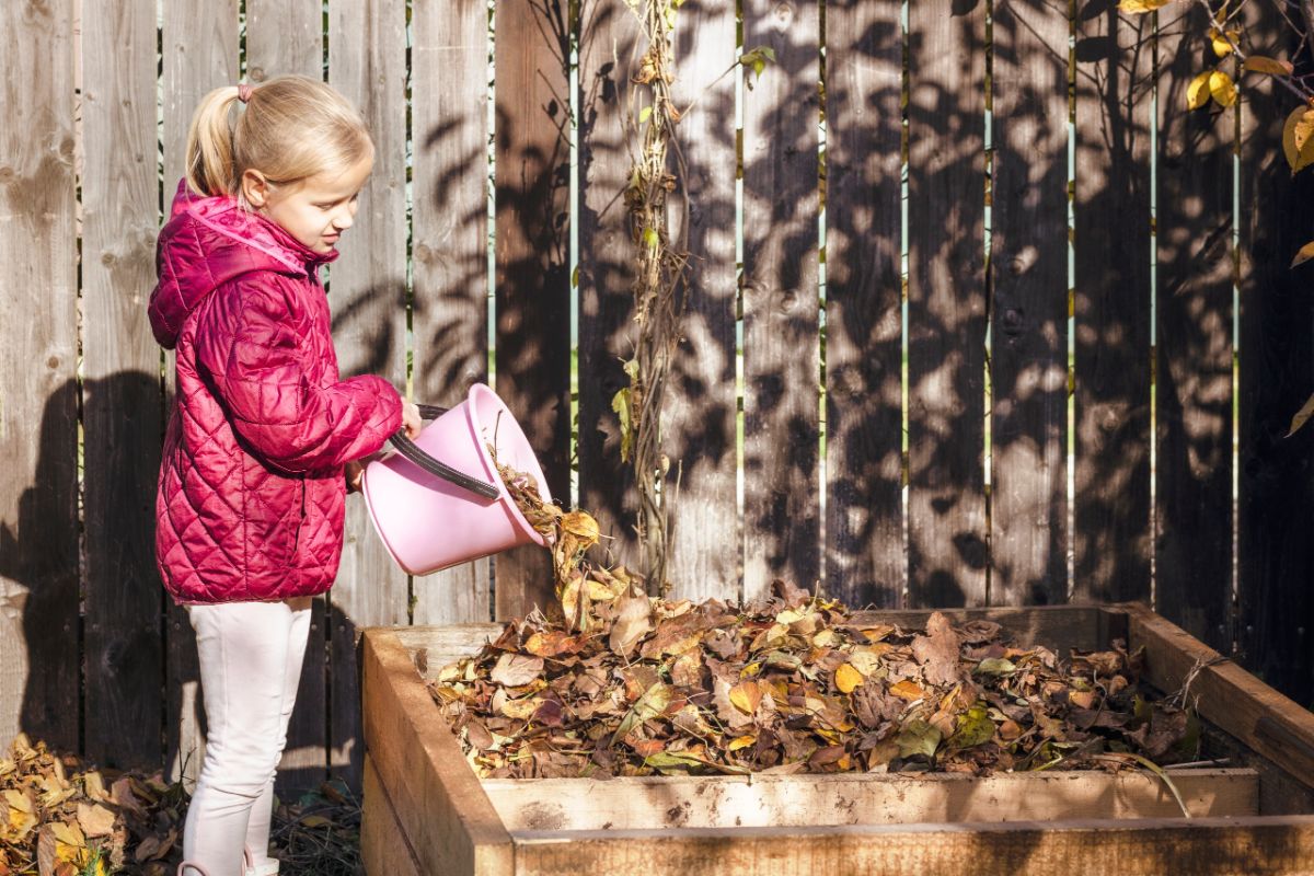 A girl adding leaves to a compost bin