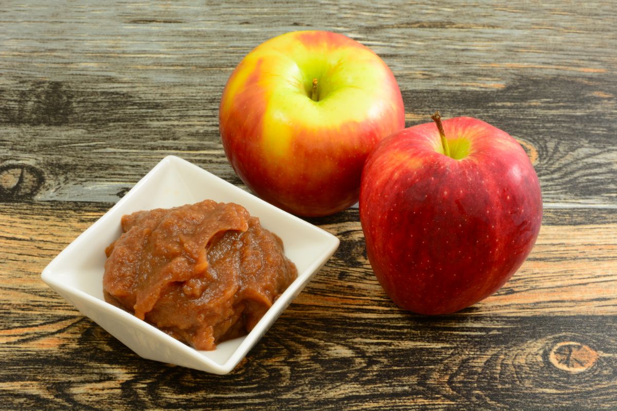 A fresh apple next to a dish of apple butter