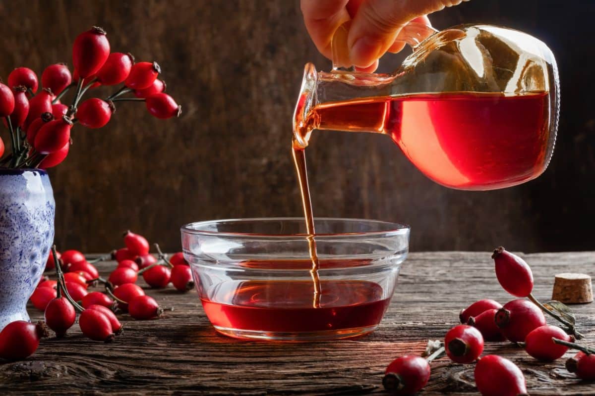 Rose hip syrup pouring into a glass bowl