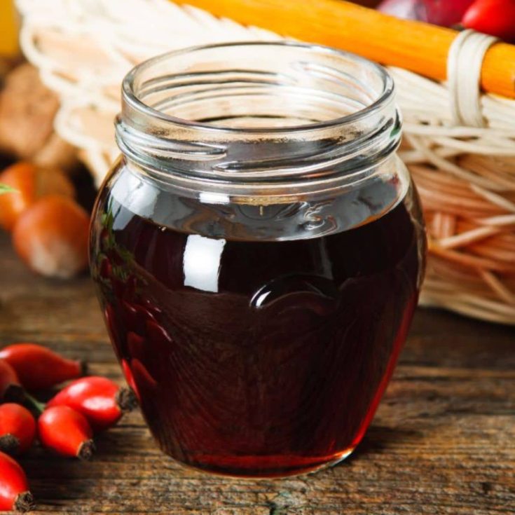 Rose hip syrup in a glass jar.