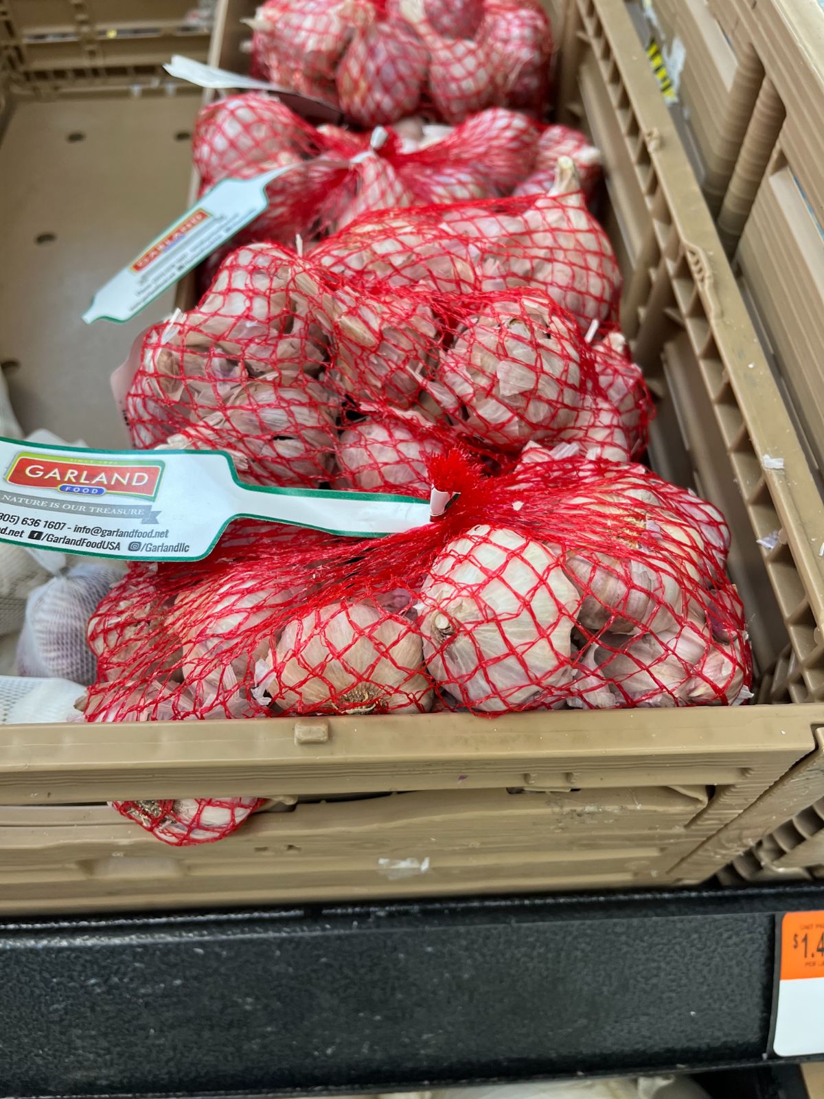 A grocery store bin with garlic in net bags