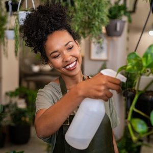 A young woman spraying her houseplants.