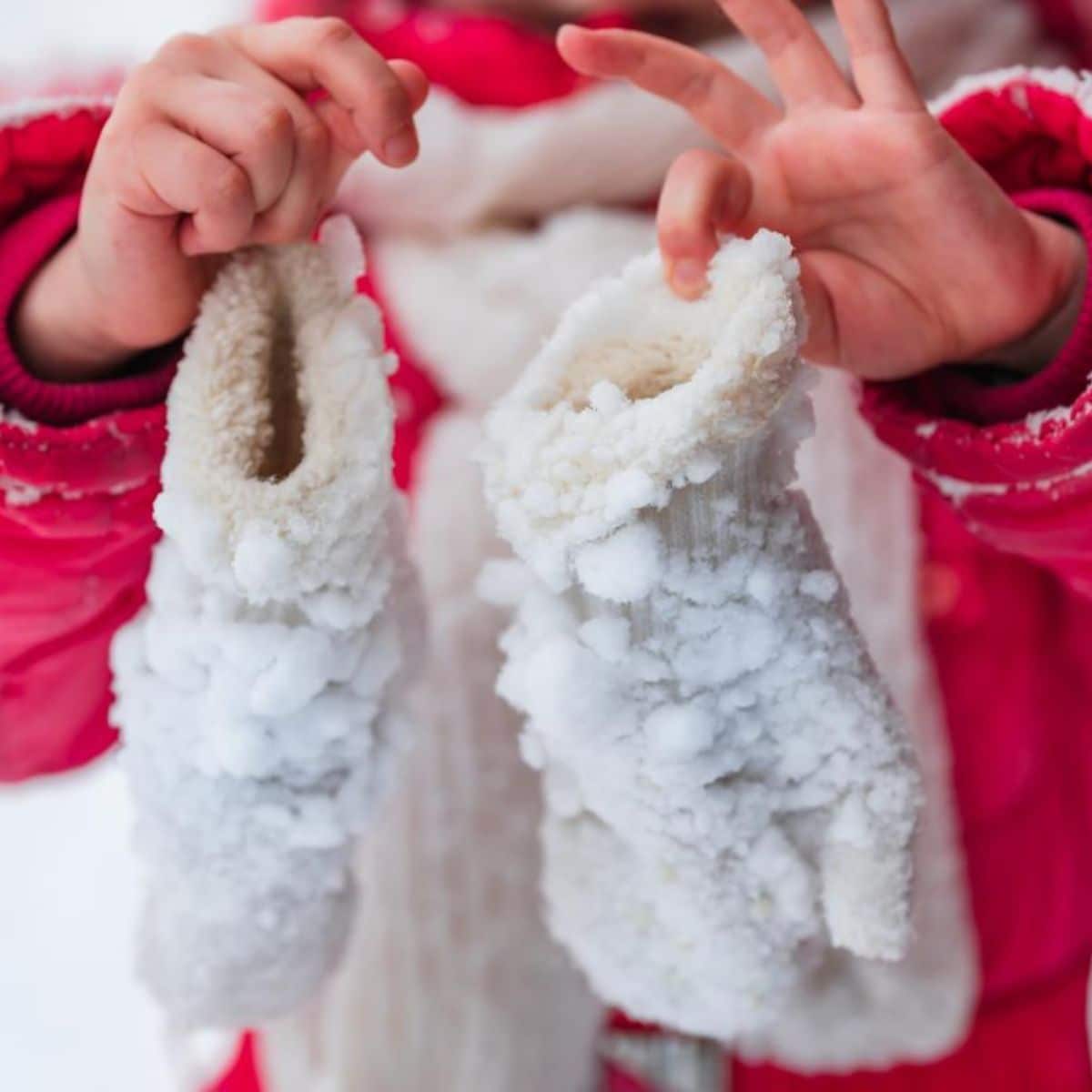 A kid is holding icy mittens.