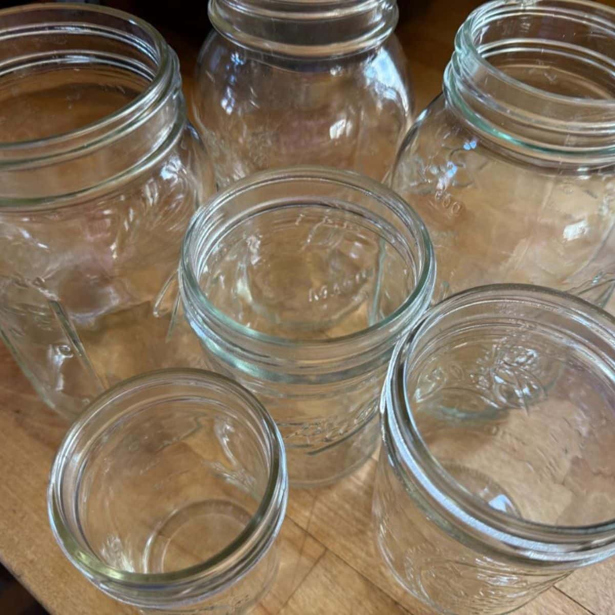 A bunch of glass canning jars on the table.